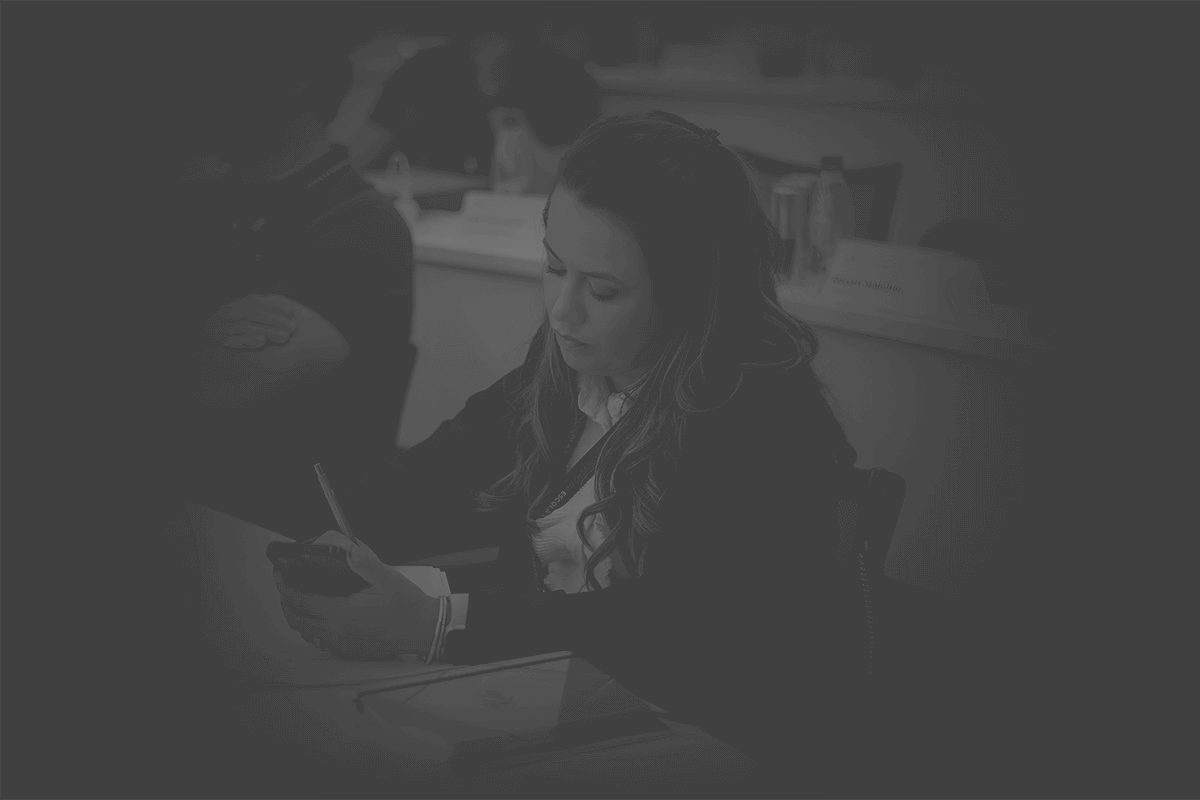 Keila Carvalho, fundadora da Mentoria Millimetrika, concentrada enquanto escreve em um caderno durante uma sessão de treinamento ou workshop. Ela está cercada por outras pessoas em um ambiente de aprendizado, refletindo seu compromisso com o desenvolvimento pessoal e profissional.